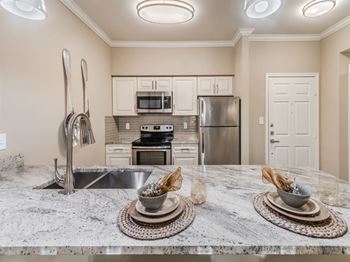 A kitchen with a marble countertop and stainless steel appliances.